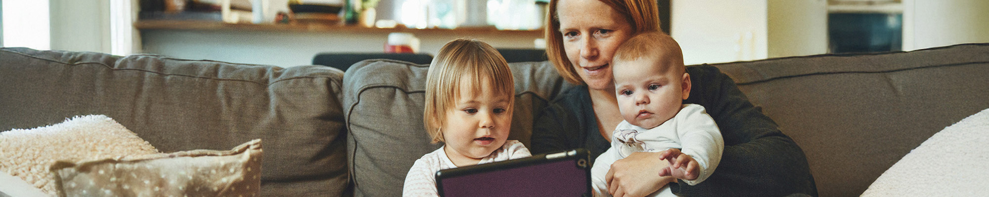 Mother reading to a toddler and baby.