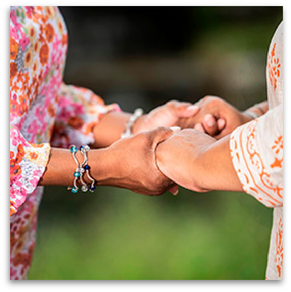 Two women holding hands for emotional support.
